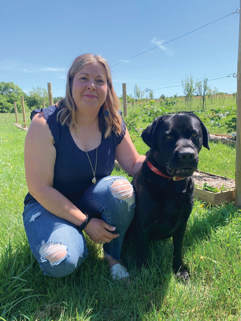 Crystal Dugas with her dog at Black Dog Farm in Marshfield, Missouri. She grows a variety of fruits and vegetables that are sold at local retailers like Mama Jeans Natural Market in Springfield. Photo by Amanda Bradley.