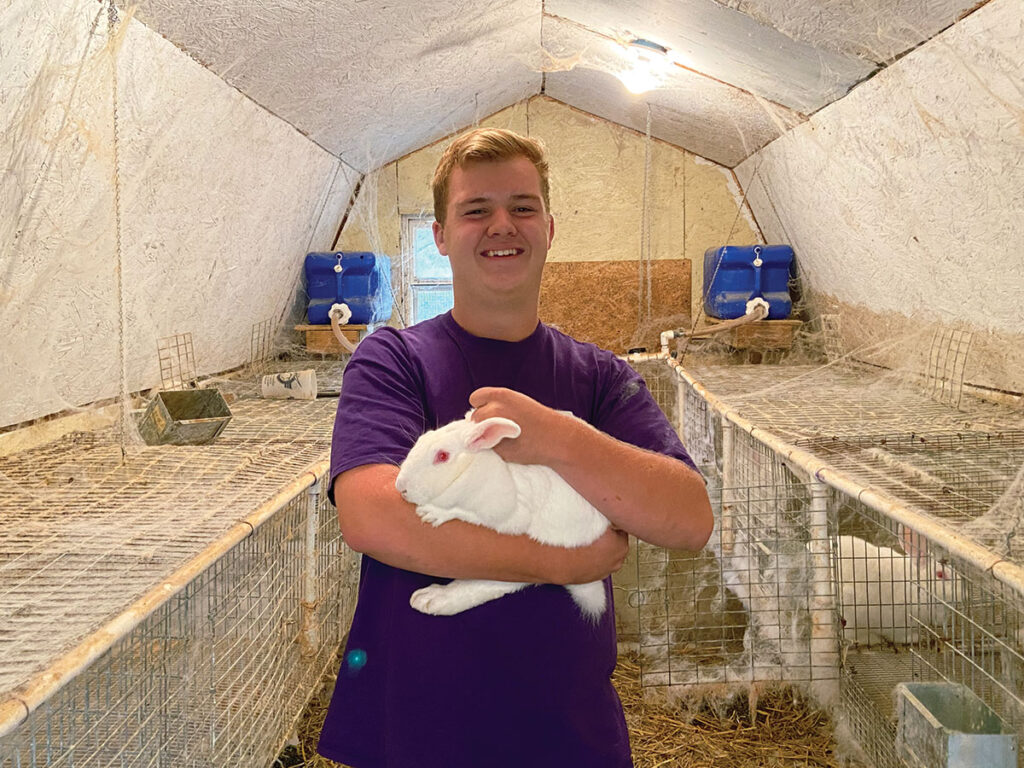 Cason Frisby with one of his rabbits. Next year he hopes to focus on rabbit production and it will be his first business. Photo by Mekiya Walters.