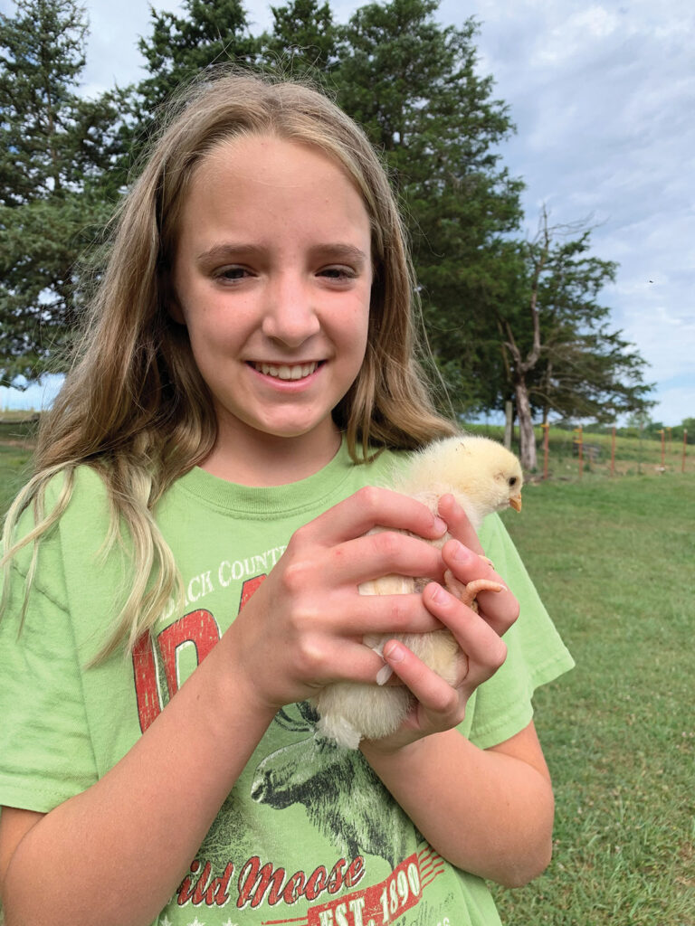 Olivia Rumfelt holding a baby chick. Photo by Amanda Bradley.