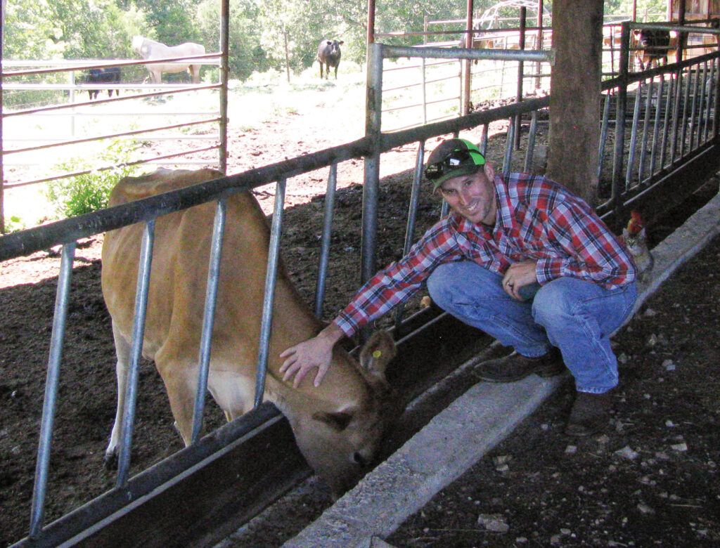 Chris Crandall petting their Jersey milk cow. Photo by Brenda Brinkley. 