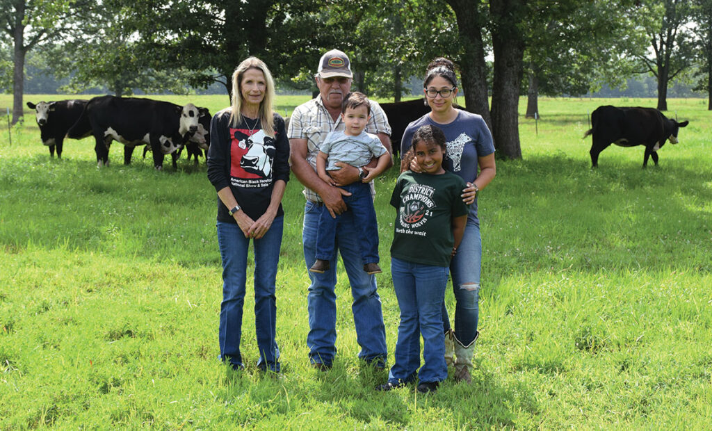 Three generations of the Studdard family work to raise high-quality Black Herefords. Pictured, from left, are Barb Studdard, John Studdard (holding grandson Michael), and Barb and John’s daughter Maria and granddaughter Shandon. Photo by Jessica Wilson.