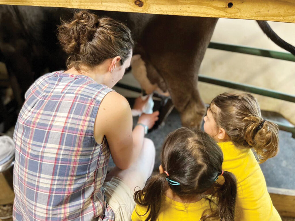 A mother milking a cow as her two daughters watch at the Dogwood Hills Guest Farm in Harriet, Arkansas. Submitted Photo. 