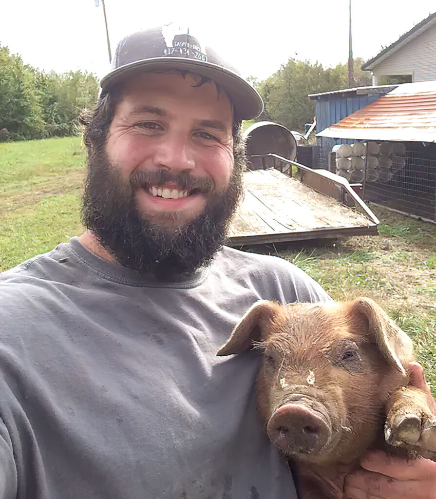 Preston Walker of P-C Hog Farm LLC with one of his hogs. Submitted Photo.