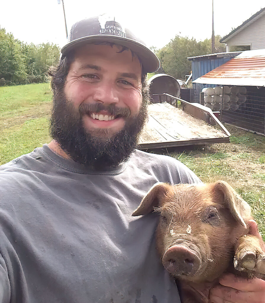 Preston Walker of P-C Hog Farm LLC with one of his hogs. Submitted Photo. 