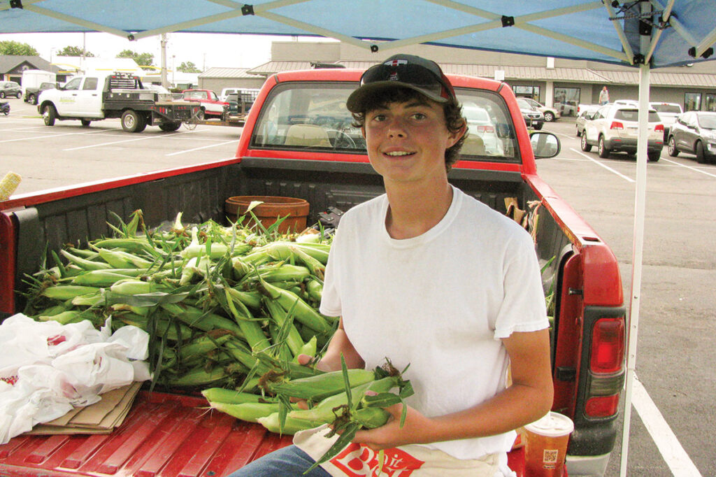 Boone Manary offers customers fresh-from-the-farm sweet corn. Photo by Brenda Brinkley. 